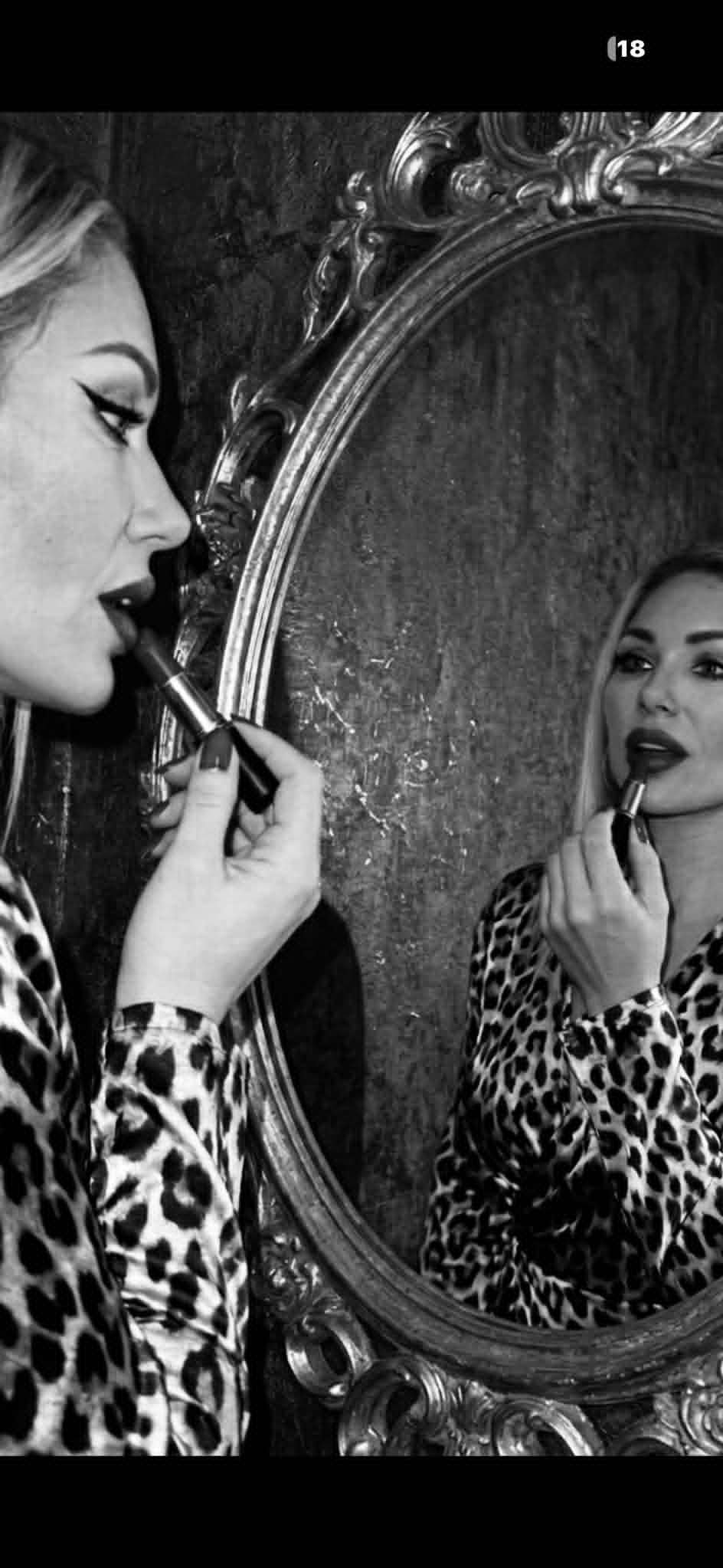 Danielle applying lipstick in a mirror wearing leopard print.